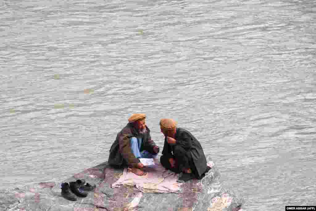 Afghan men sit by the Kokcha River in Fayzabad.