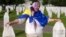 A Bosnian Muslim woman mourns next to the graves of her children and husband at the Srebrenica Memorial Center in Potocari.