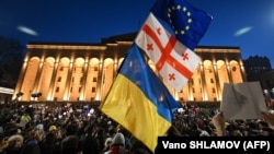 Протестующие размахивают флагами Грузии, Украины и Европы во время демонстрации в Тбилиси 8 марта 2023 года