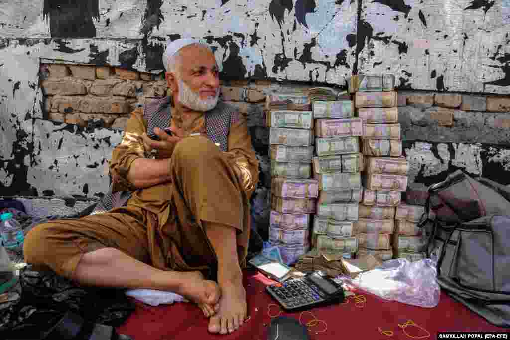 An Afghan currency dealer sits next to old bank notes at a local market in Kabul.