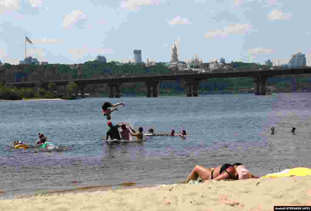 Local residents sunbathe on the beach and swim in the Dnieper River in Kyiv.
