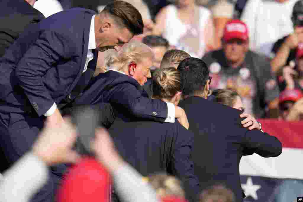 Blood was visible on Trump&#39;s right ear and cheek. He was whisked by the Secret Service agents into a waiting car and left the venue