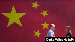 Граѓаните на Белград поминуваат покрај кинеското знаме поставено пред посетата на кинескиот претседател Си Џинпинга во главниот град на Србија, 7 мај 2024 година.