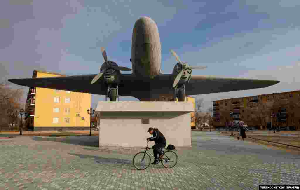 A man cycles past a Soviet-era aircraft installed as a monument in Baikonur, Kazakhstan.