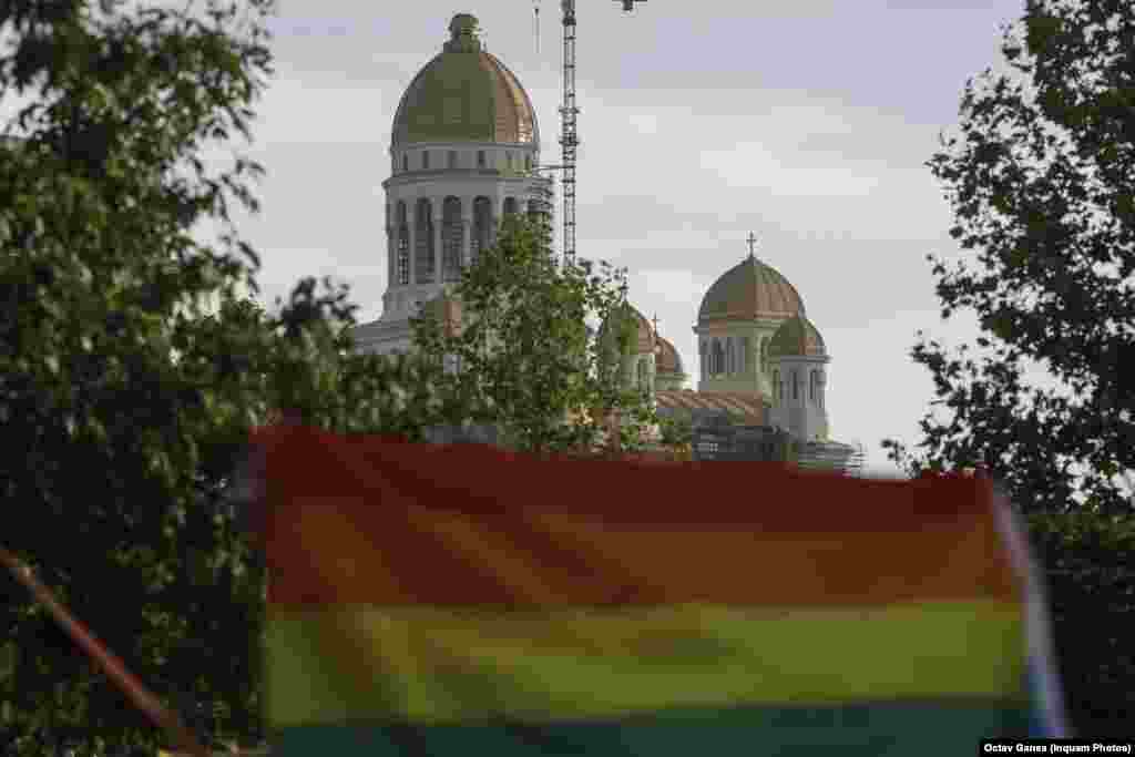 Steagul comunității LGBT flutură în prim-planul turlei Catedralei Mântuirii Neamului.