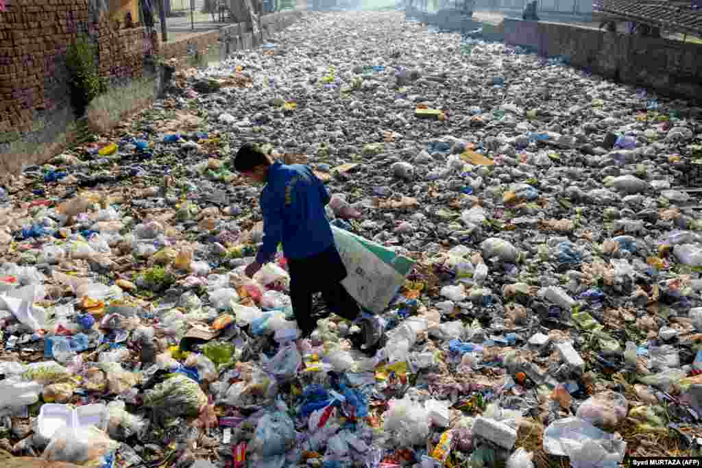 A waste picker scouts for recyclable junk from a sewage drain used as a garbage dump at a slum area in Lahore, Pakistan.