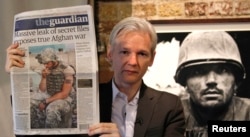 Julian Assange arată ediția din 26 iulie 2010 a ziarului The Guardian în timpul unei conferințe de presă la Frontline Club din centrul Londrei.