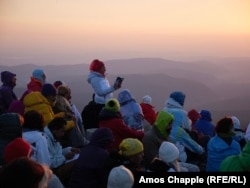 A female member of the White Brotherhood leads a prayer session on a peak in the Rila Mountains as the sun rises.