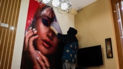 O cosmeticiană din Kabul, Afganistan, înlătură un poster dintr-un salon de înfrumusețare, pe 24 iulie 2023.