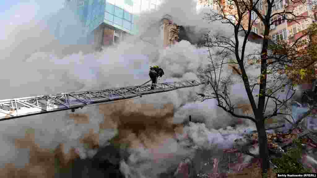 The same day, a firefighter climbs a ladder as he extinguishes a blaze in a residential area in Kyiv that was hit by a Shahed-136 drone.