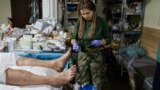 Цей метушливий польовий госпіталь поблизу Бахмуту Донецької області був знятий фотографом агенції AP 26 лютого 2023 року.<br />
<br />
На передньому плані &ndash; медикиня із косичками на ім&rsquo;я Яна Рихліцька надає допомогу пораненому