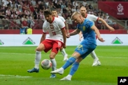 Ukrajinac Oleksandr Zinčenko šutira loptu ispred Poljaka Bartoša Berešinskog tokom međunarodne prijateljske fudbalske utakmice između Poljske i Ukrajine na Nacionalnom stadionu u Varšavi, Poljska, 7. jun 2024.