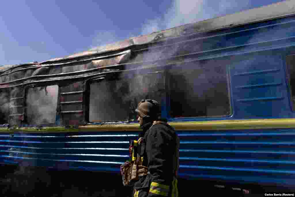 A firefighter near a smoldering train carriage.