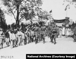 Harbord (seen adjusting collar on left) and other members of the mission enter a courtyard in Echmiadzin, a town just west of Yerevan. An American flag can be seen flying over the gate as part of the reception.