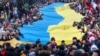 Люди несуть гігантський український прапор на знак протесту проти російського вторгнення в Україну під час святкування незалежності Литви. Вільнюс, 11 березня 2022 року