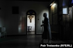 An elderly woman prays in the Catholic church.