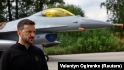 Volodimir Zelenszkij ukrán elnök egy F–16-os vadászgép előtt beszél a sajtónak egy titkos helyszínen, Ukrajnában augusztus 4-én