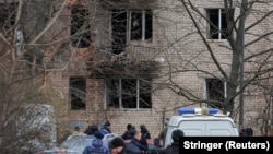 Rescue workers and investigators gather near a damaged residential building in St. Petersburg following an alleged drone attack on March 2