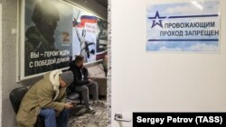 Россия, Москва. Сидящие перед пунктом отбора на военную службу по контракту на улице Яблочкова. Иллюстрация.