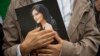 A mourner clutches a portrait of Mahsa Amini.