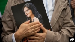 A mourner clutches a portrait of Mahsa Amini.