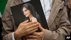 A demonstrator holds a portrait of Mahsa Amini at a protest rally following her death.