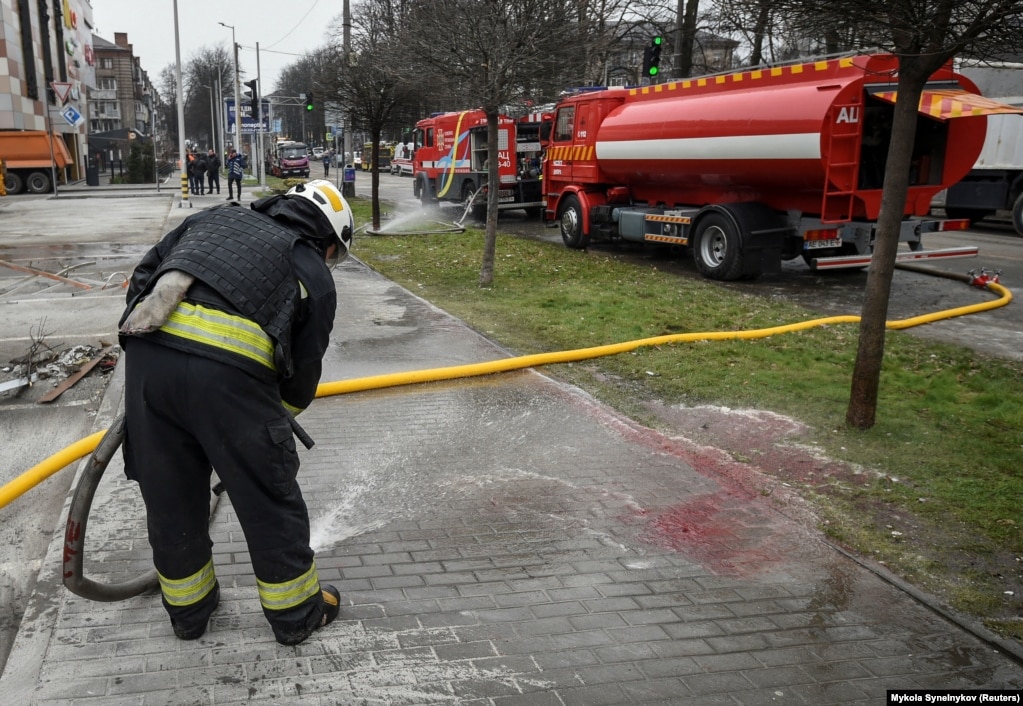 Un operatore dei servizi di emergenza lava il sangue dalle strade di Dnipro.