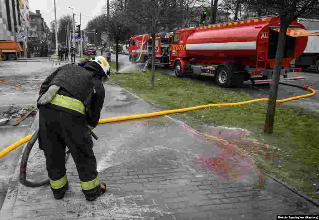 An emergency services worker washes the blood from the street in Dnipro.