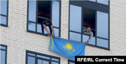 Деразага Қозоғистон байроғини илаётган фуқаролар.