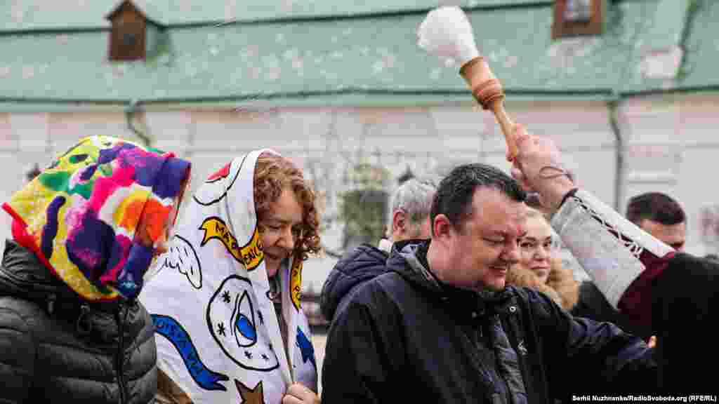 Священник ПЦУ освячує&nbsp;&nbsp;водою вірян та їхні великодні кошики після служби в Успенському соборі Києво-Печерської лаври