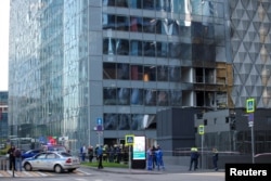 Сотрудники российских экстренных служб собираются возле поврежденного в ходе атаки беспилотника офисного здания в деловом центре «Москва-Сити». Москва, 30 июля 2023 года