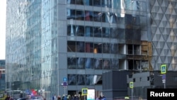Сотрудники экстренных служб собираются возле поврежденного офисного здания в Москва-Сити после сообщения об ударе беспилотником в Москве. Россия, 30 июля 2023 г.