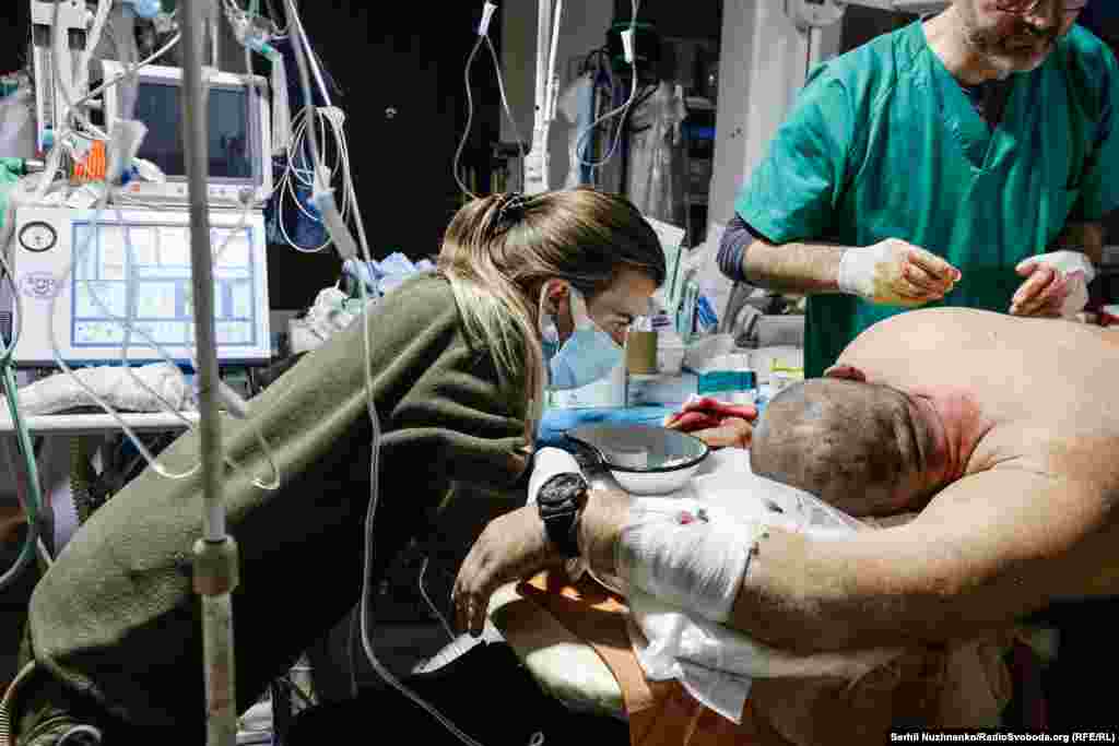 Бойова медикиня заспокоює пораненого бійця під час надання допомоги. Бахмут, листопад 2022 року