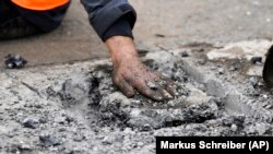Një protestues, pjesëtar i grupit ambientalist "Last Generation" (Gjenerata e Fundit), e ka ngjitur dorën në asfaltin e një rruge në Berlin, për të ndaluar trafikun.