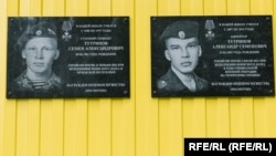 Plăci comemorative pe școala din satul Kuratovo, unde au studiat Semion (stânga) și Aleksandr Tutrinov.