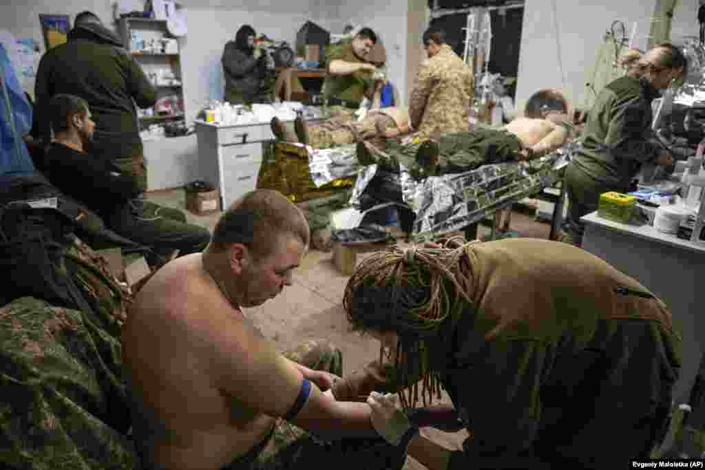 A medic treats wounded soldiers in a field hospital room.