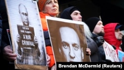 Protestuesit duke mbatur forografi të Vladimir Putinit dhe Aleksei Navalnyt gjatë një tubimi para Konsullatës ruse në Nju Jork, pas njoftimit për vdekjen e kritikut të Kremlinit më 16 shkurt.
