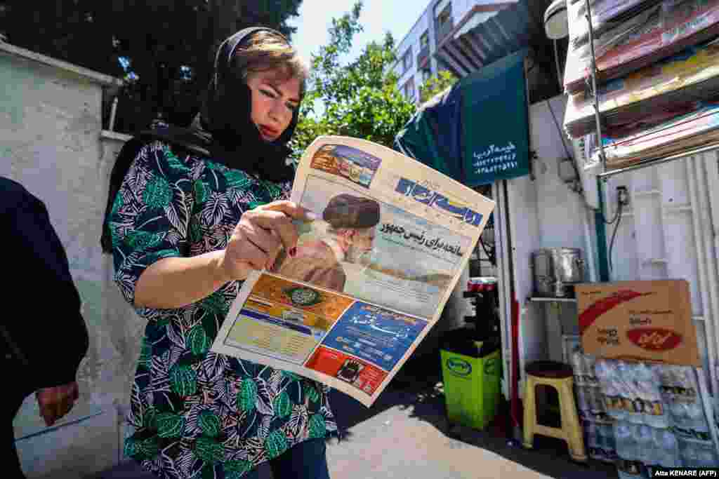 O femeie din Iran citește ziarul în care scrie, pe prima pagină, despre accidentul de elicopter în care a murit președintele.&nbsp; &nbsp;