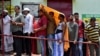 Ljudi se pokrivaju kako bi se sakrili od vrućine dok čekaju u redu ispred biračkog mjesta da daju svoje glasove tokom šeste faze opštih izbora u Indiji, vrelog ljetnog dana u Bhubaneswaru, Indija, 25. maja 2024. 
