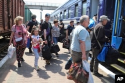 Люди сідають в евакуаційний потяг на залізничній станції в Херсоні. 6 червня 2023 року