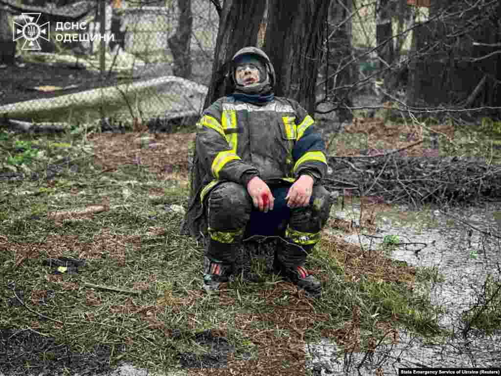 Поранений внаслідок атаки на Одесу рятувальник сидить під деревом. Його товариші загинули внаслідок цього обстрілу. Державна служба України з надзвичайних ситуацій надає можливість проводити фотозйомку міжнародним ЗМІ у супроводі рятувальників