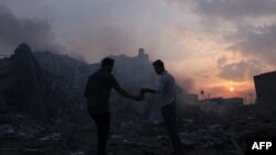 Palestinci traže stvari koje se mogu spasiti ispred ruševina zgrade uništene u izraelskim zračnim napadima u gradu Gazi 8. oktobra 2023.