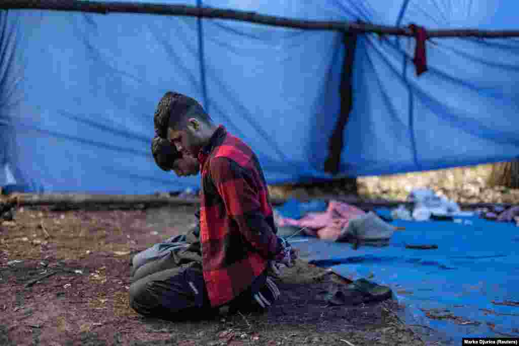 Detained migrants sit on their knees with cuffed hands at their makeshift camp close to the Serbia-Hungary border, near the city of Subotica, Serbia.