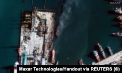 На спутниковом снимке виден уничтоженный российский военный корабль в порту Феодосия. Внизу слева возле причала находится балкер SAN COSMAS. 26 декабря 2023 года. Maxar Technologies/REUTERS