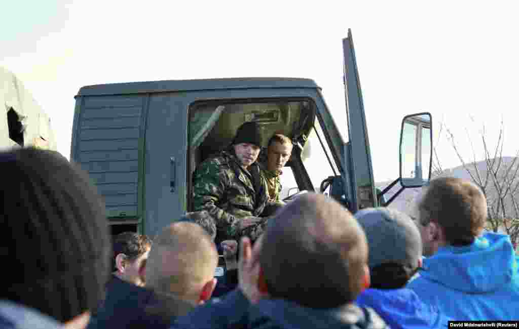 Местные жители окружили грузовик, в котором находятся украинские военные, 3 марта. Пророссийски настроенные местные жители начали выходить на улицы вместе с российскими военными без опознавательных знаков, усиливая давление на украинские силы, которые оказались в итоге изолированными на своих военных базах. В Крыму в то время около 60 процентов населения составляли этнические русские