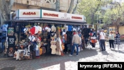 Люди у сувенирной лавки в центре Феодосии накануне начала курортного сезона, 15 апреля 2024 года