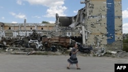 Жінка йде повз зруйновані будинки в Маріуполі, 16 серпня 2023 року