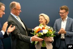 10 iunie 2024 - Ursula von der Leyen primește flori de la președintele CDU, Friedrich Merz, la o ședință a partidului după alegerile europarlamentare.