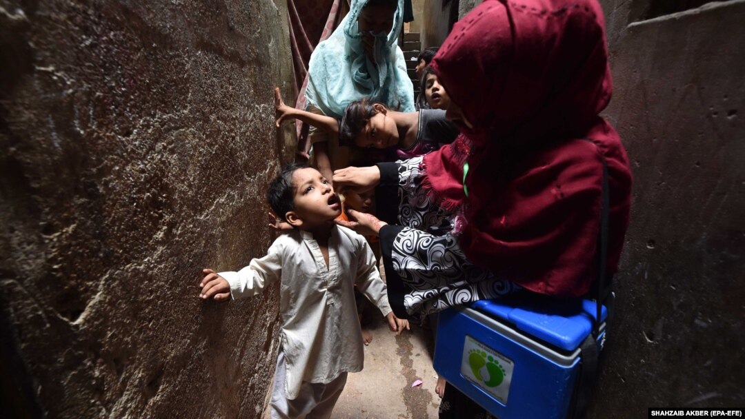 A health worker administers polio vaccine drops to a child during a door-to-door vaccination campaign in Karachi in June.