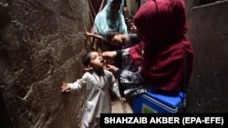 A health worker administers polio vaccine drops to a child during a door-to-door vaccination campaign in Karachi in June.